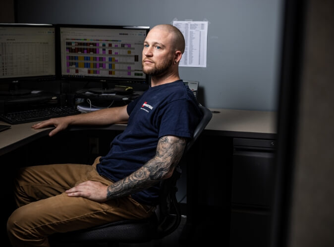 an swf industrial employee sitting at his desk looking to the left of the camera